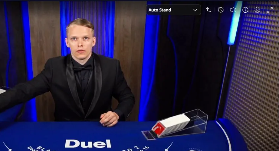 A live dealer at the Duel.com blackjack table, with the blue Duel-branded felt, card shoe and chip tray.
